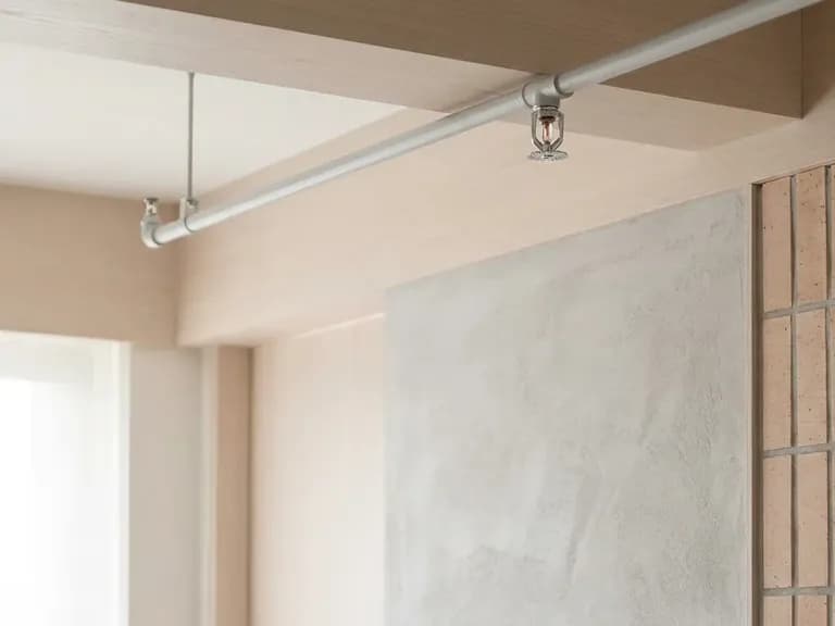 Modern konut koridorunda sprinkler başlığı ve ince yangın borusu, yangın güvenliğine vurgu yapıyor.